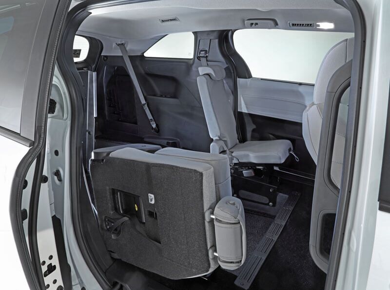 The image shows the interior of a Toyota Sienna Hybrid with the second-row seat folded forward, revealing rear-entry access to the third-row seating area.