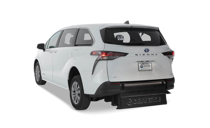A white Toyota Sienna Hybrid minivan with a rear-entry wheelchair ramp extended from the back, shown on a plain white background.